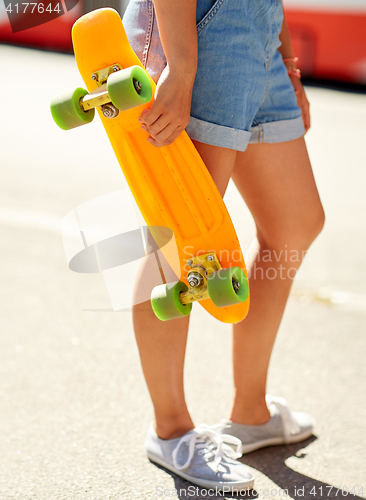 Image of teenage girl with skateboard on city street