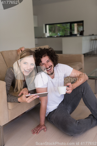 Image of couple relaxing at  home with tablet computers