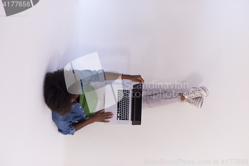 Image of african american woman sitting on floor with laptop top view