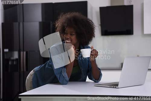 Image of smiling black woman in modern kitchen