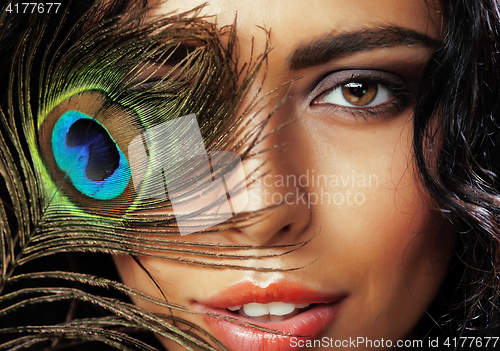 Image of young sensitive brunette woman with peacock feather eyes close up on green smiling, lifestyle people concept