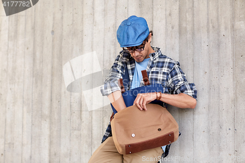 Image of hipster man looking for something in his bag