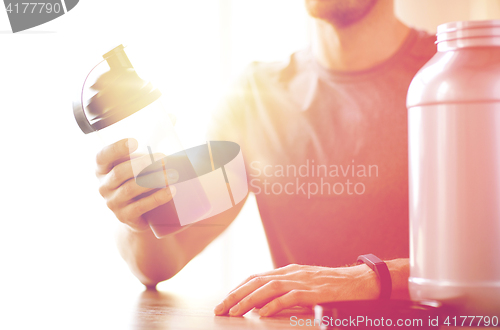 Image of close up of man with protein shake bottle and jar