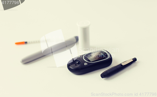 Image of close up of glucometer, insulin pen and syringe