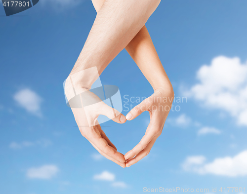 Image of woman and man hands making heart symbol