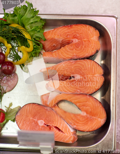 Image of salmon fish fillet in metal tray on ice at grocery