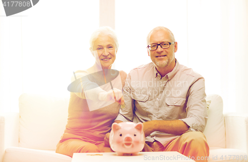 Image of senior couple with money and piggy bank at home