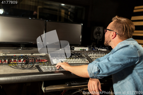 Image of man at mixing console in music recording studio