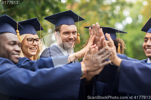 Image of happy students in mortar boards making high five