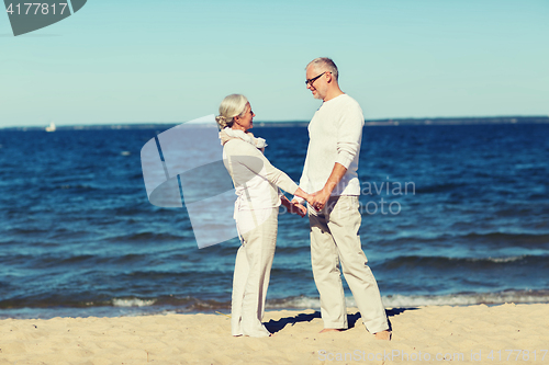 Image of happy senior couple holding hands on summer beach