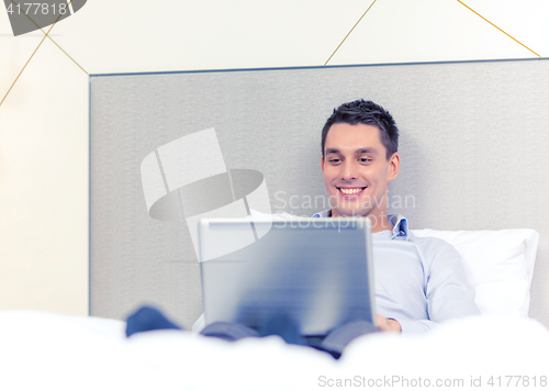 Image of happy businesswoman with laptop in hotel room