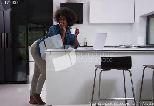 Image of smiling black woman in modern kitchen