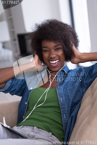 Image of African american woman at home in chair with tablet and head pho