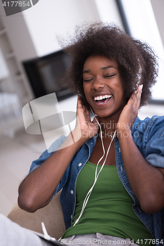 Image of African american woman at home in chair with tablet and head pho