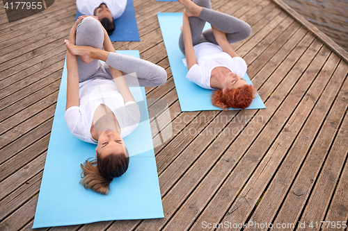 Image of group of people making yoga exercises outdoors