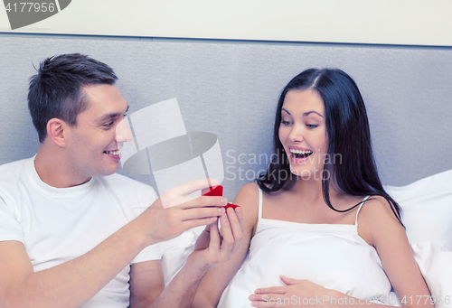 Image of man giving woman little red box and ring in it