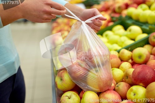 Image of woman with bag buying apples at grocery store