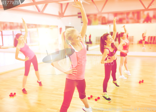Image of group of smiling women stretching in the gym