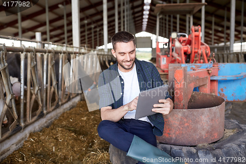 Image of young man with tablet pc and cows on dairy farm