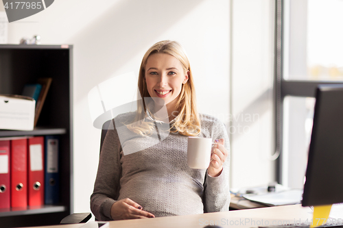 Image of pregnant businesswoman with cup of tea at office