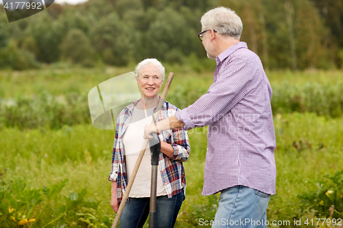 Image of senior couple with garden tools working at farm