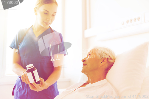 Image of nurse giving medicine to senior woman at hospital