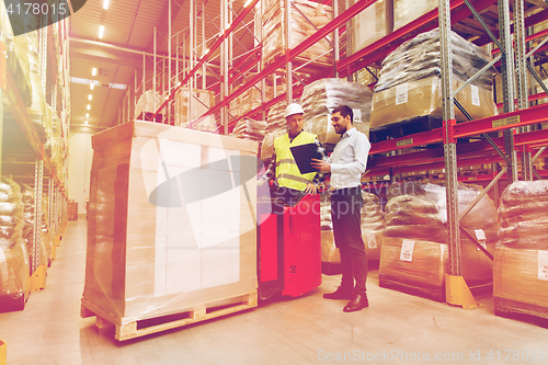 Image of worker on forklift and businessman at warehouse