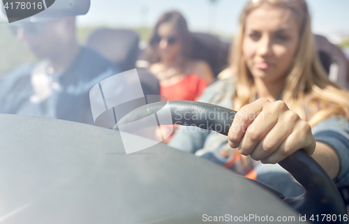 Image of happy friends driving in convertible car