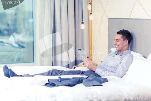 Image of happy businesswoman with tablet pc in hotel room