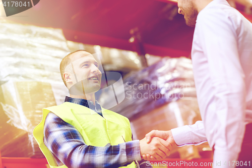 Image of worker and businessmen with clipboard at warehouse