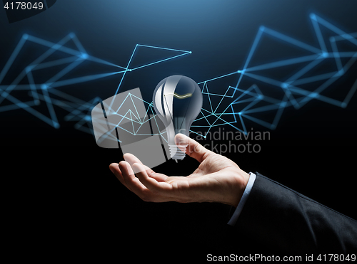 Image of businessman hand with bulb over dark background