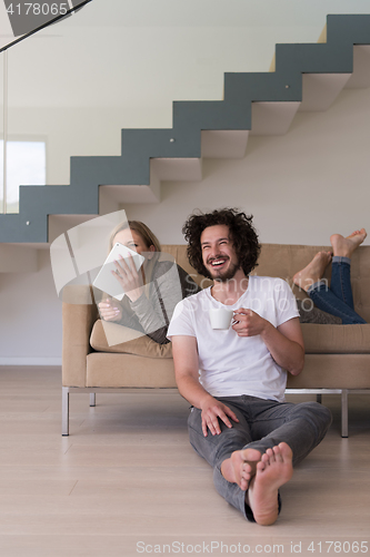 Image of couple relaxing at  home with tablet computers