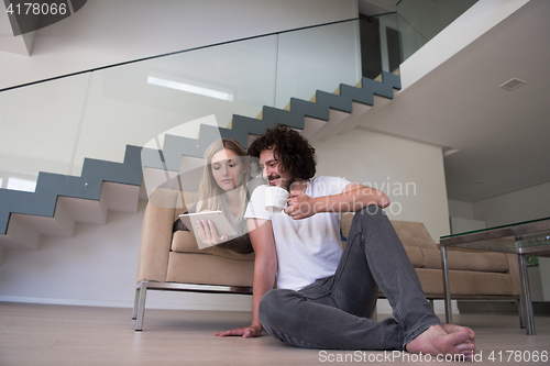 Image of couple relaxing at  home with tablet computers