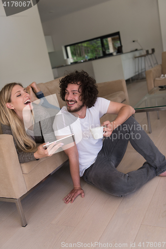 Image of couple relaxing at  home with tablet computers