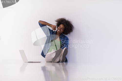 Image of african american woman sitting on floor with laptop