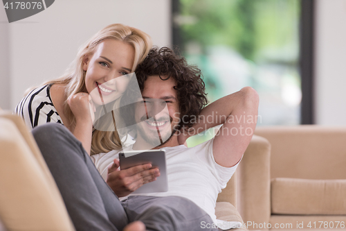 Image of couple relaxing at  home with tablet computers