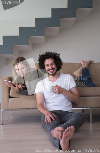 Image of couple relaxing at  home with tablet computers