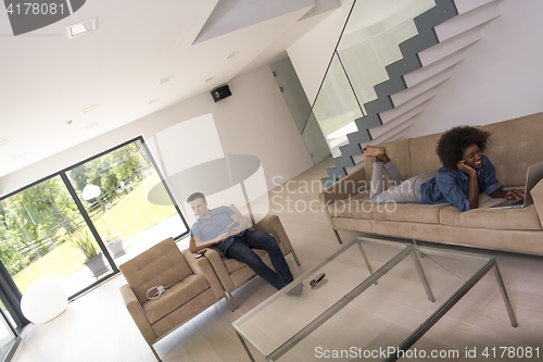 Image of young multiethnic couple relaxes in the living room