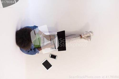 Image of african american woman sitting on floor with laptop top view