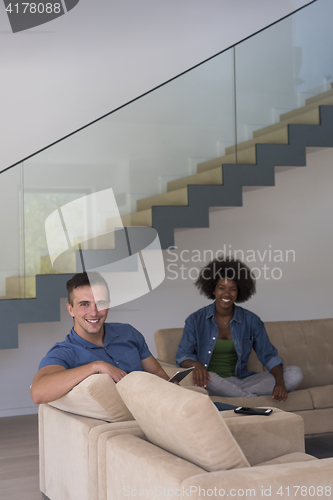 Image of multiethnic couple relaxing at  home with tablet computers