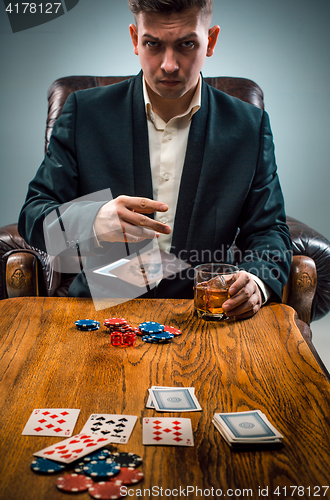 Image of The man, chips for gamblings, drink and playing cards