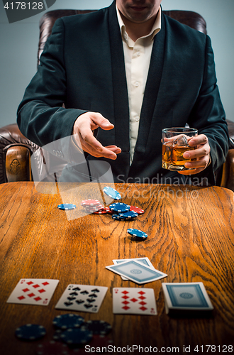 Image of The man, chips for gamblings, drink and playing cards