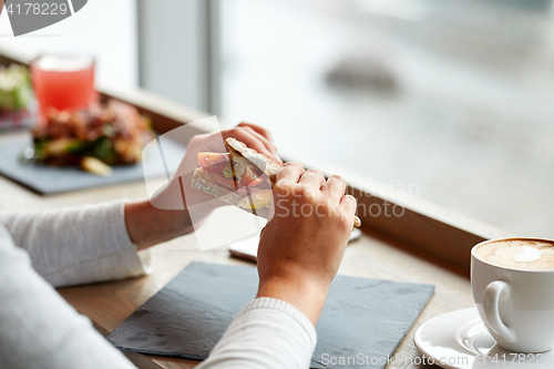 Image of woman eating salmon panini sandwich at restaurant