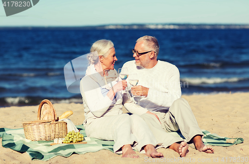 Image of happy senior couple having picnic on summer beach