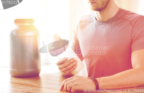 Image of close up of man with protein shake bottle and jar