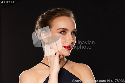 Image of beautiful woman in black over dark background