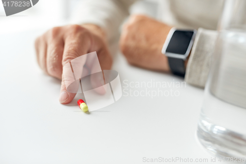 Image of close up of old man hand with pill and smart watch