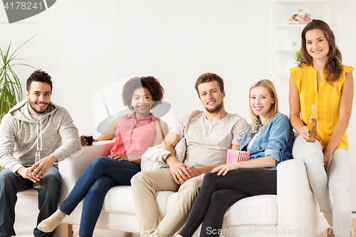 Image of happy friends with popcorn and beer at home