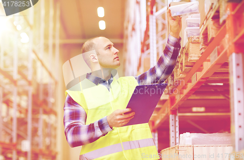 Image of man with clipboard in safety vest at warehouse