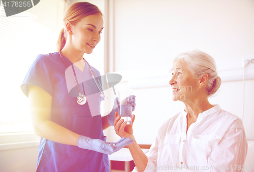 Image of nurse giving medicine to senior woman at hospital